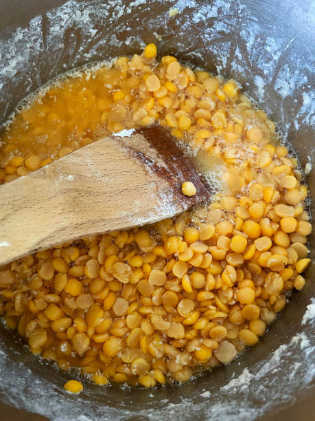 immagine a tutto telaio di spatola di legno che mescola piselli gialli divisi e acqua bollente nella padella di cottura, acqua scintillante che riduce in casseruola, vista elevata - split pea foto e immagini stock