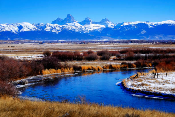 chaîne de montagnes grand teton avec rivière bleue incurvée dans la neige avec le ciel - wyoming teton range jackson hole autumn photos et images de collection