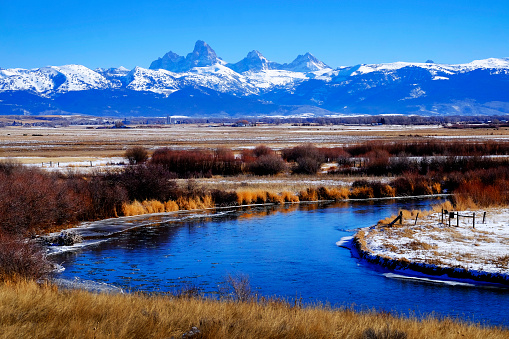 Grand Teton Mountain Range with curving blue river in snow with sky