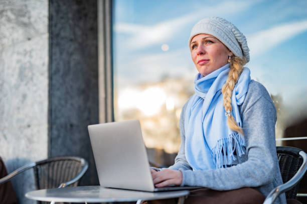 Woman using laptop during cold day in front of coffee bar stock photo