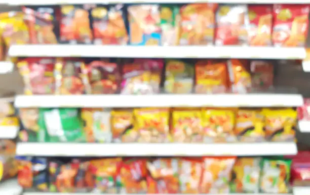 blurred view of assorted brand and type of instant noodles on shelf rack display in the convenience store. instant noodles brands on the shelf in supermarket for sell.
