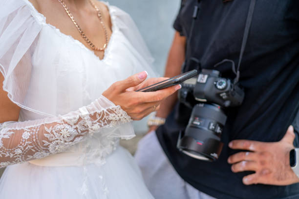 la mariée en robe blanche tient un smartphone à la main. - wedding bride buying caucasian photos et images de collection