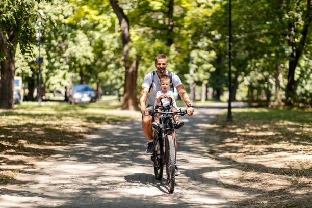 istock Morning routine and active family mornings during summer vacations. Dad rides the boy in a bicycle basket and they both look at the camera and laugh. Healthy habits and an active day for loved ones 1340060381