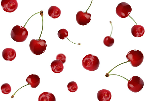 Fresh ripe cherries falling on white background
