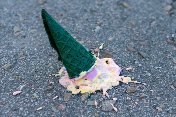 istock Bright ice cream in a green cone fell on the asphalt. Side view. Close-up. 1340062737