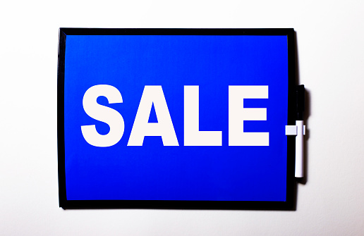 SALE written in white on a blue tablet on a white background