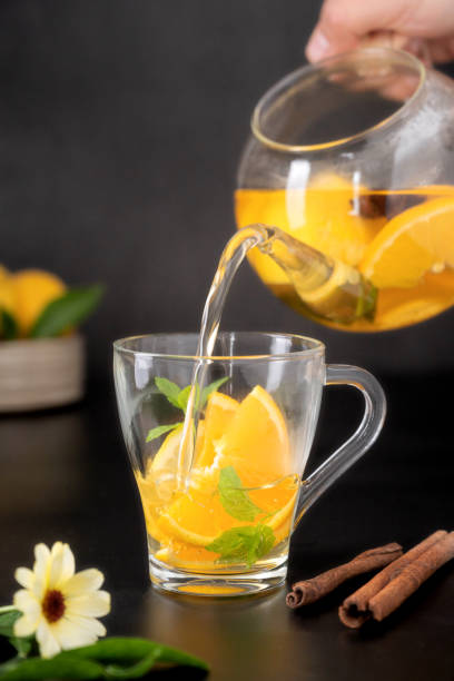 istock Glass cup with fruit herbal tea on black background. Calendula healthy tea 1340066383