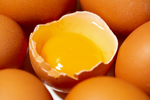 fresh chicken eggs on white background, one broken egg, closeup horizontal
