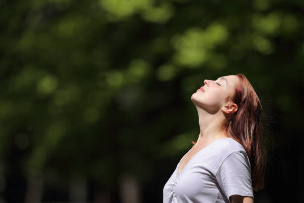 Woman breathing and heating under sun in a park stock photo