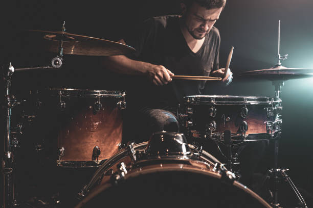 istock A man plays drums on stage in the dark with stage spotlights. 1340067703