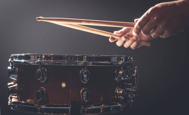 istock Snare drum and drummer's hands hitting drumsticks against a dark background. 1340067706