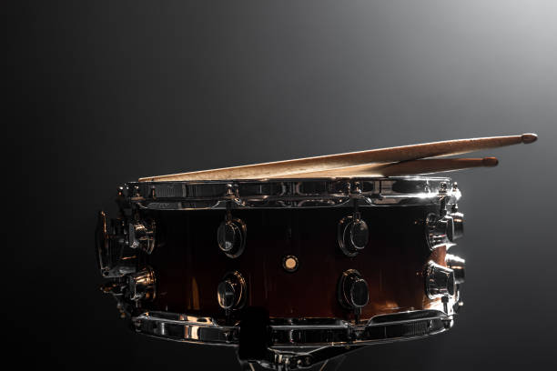 Close-up snare drum and drum sticks on a dark background. Close-up, snare drum, percussion instrument against a dark background with stage lighting, copy space. snare drum stock pictures, royalty-free photos & images