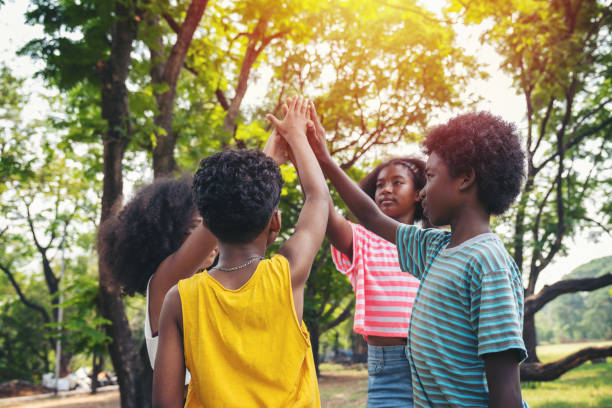 Group of children joining hands together standing in the park, Kids playing teamwork outdoor. Group of children joining hands together standing in the park, Kids playing teamwork outdoor. african american kids stock pictures, royalty-free photos & images