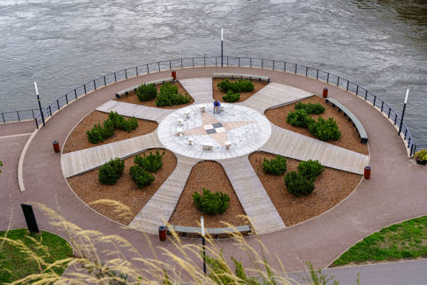 istock Public park by the river with decorative plants and benches to sit on. 1340068303