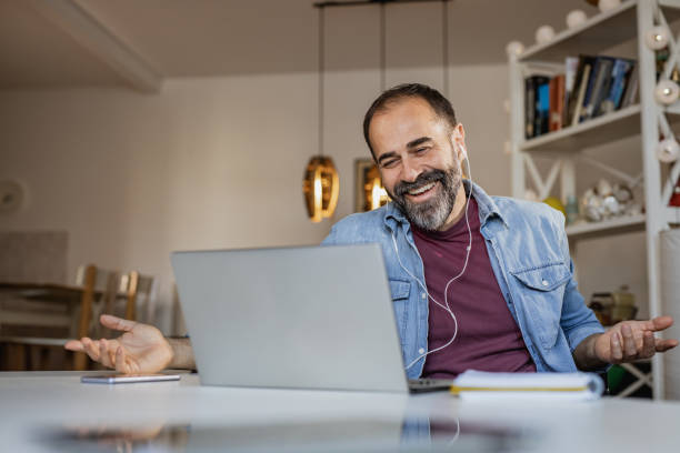 istock Mature man smiling and talking on a video call on the laptop 1340071681