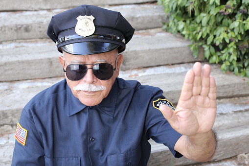 Senior American policeman showing stop hand sign.
