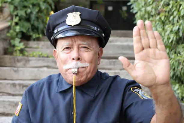 Senior American policeman showing stop hand sign.