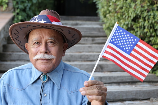 Senior American cowboy holding the national flag.