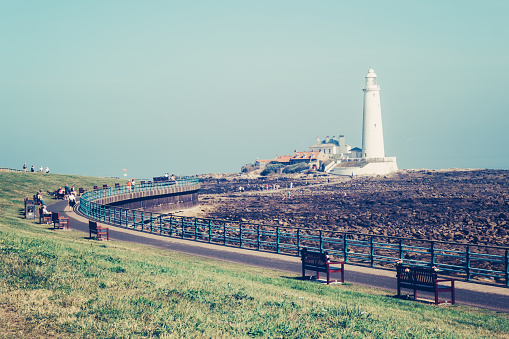Whitley Bay, United Kingdom: September 07, 2021: Tourists and locals visiting the beach and coastline of Whitley Bay in the Northumberland region of England, with views towards St Mary's Lighthouse.