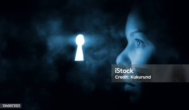 The Womans Face In The Dark Looks Through The Keyhole Glowing Blue Mysterious Light Stock Photo - Download Image Now