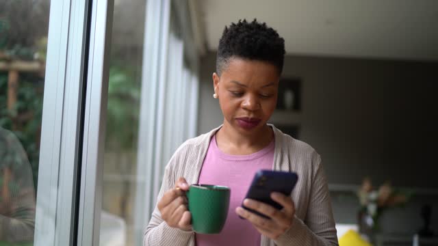 Woman using smartphone and contemplating at home