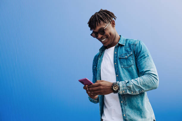 istock african man in sunglasses typing sms over blue background, 5g internet concept, high speed internet on phone 1340077663