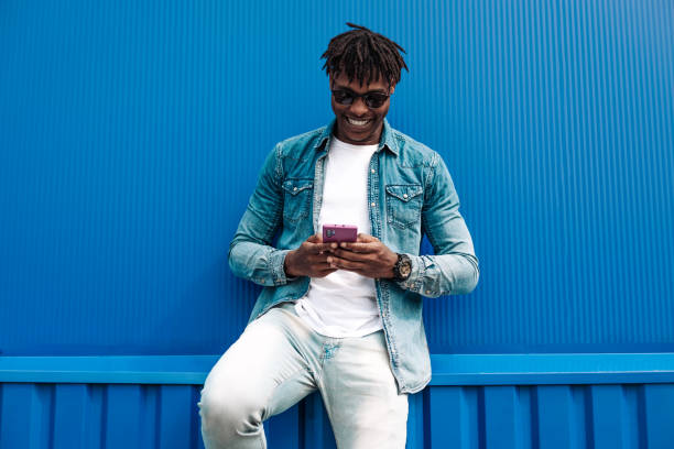istock african man typing sms on blue background, 5g internet concept, high speed internet on phone 1340077733