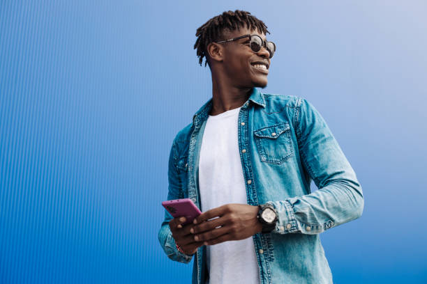 istock african man in sunglasses typing sms over blue background, 5g internet concept, high speed internet on phone 1340078894