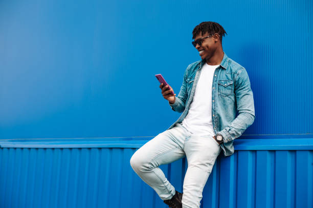 istock african man typing sms on blue background, 5g internet concept, high speed internet on phone 1340078960
