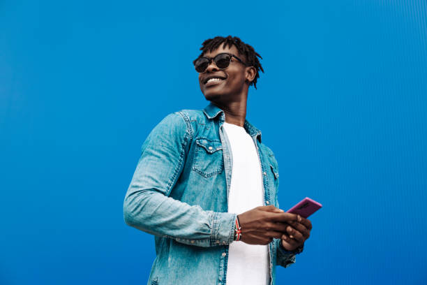 istock african man typing sms on blue background, 5g internet concept, high speed internet on phone 1340079158