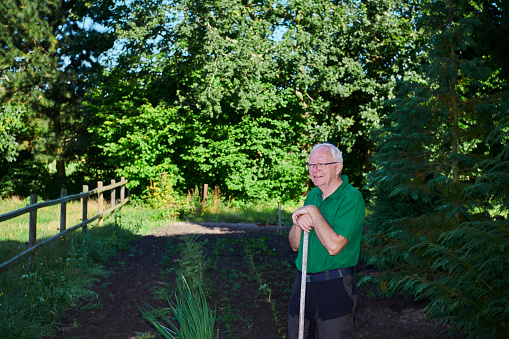 Retired man standing enjoying his garden