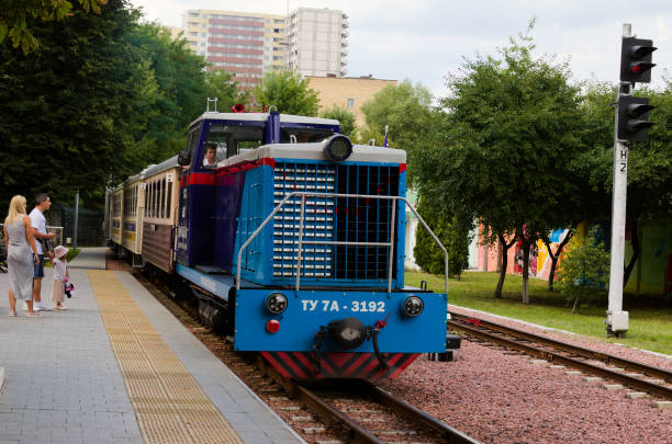 coulpe avec petite fille attendent le train. locomotive diesel tu-7a avec plusieurs voitures qui sont des approches de la gare. chemin de fer pour enfants de kiev à voie étroite - coulpe photos et images de collection