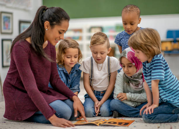 istock Diverse group of kindergarten children reading a book with a teacher 1340083564