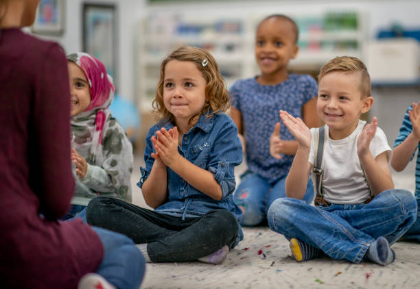 istock Multi ethnic preschool children clapping their hands in class 1340083610