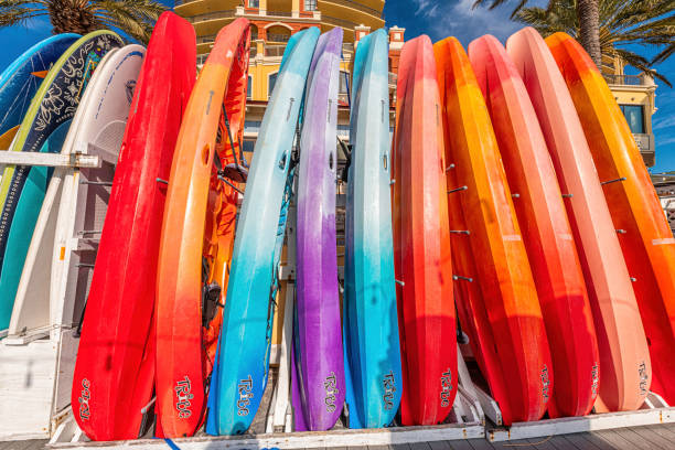 Row stack of many colorful red blue purple yellow kayak boats in Florida resort city town village with Tribe sign on Harbor Boardwalk in summer Destin, USA - January 13, 2021: Row stack of many colorful red blue purple yellow kayak boats in Florida resort city town village with Tribe sign on Harbor Boardwalk in summer kayak surfing stock pictures, royalty-free photos & images