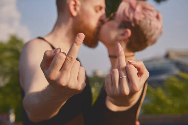 Young couple gesturing fuck off while kissing stock photo