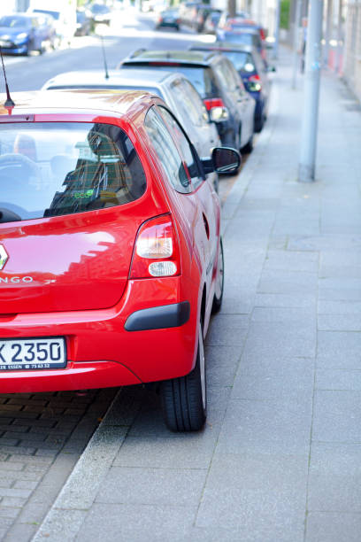 Incorrect parked red car partially on sidewalk in street Ruhrtalstrasse in Essen
