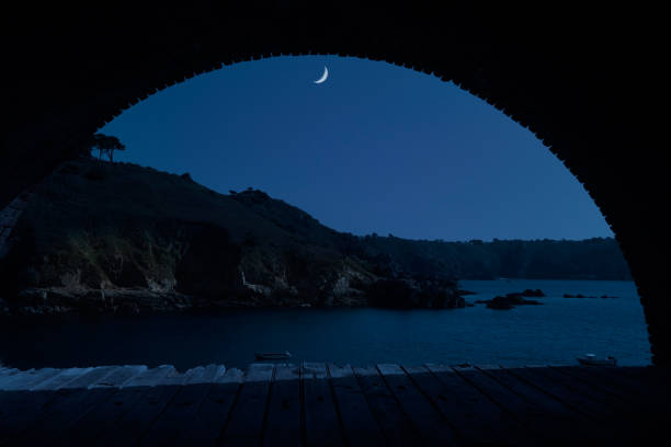 Quarter moon over Saints Bay Harbor in Guernsey, an island in the English Channel