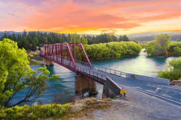 Bridge Clyde over Clutha river in the New Zealand Beautiful sunset over the Clyde bridge on the river Clutha with Southern Alps peaks on the horizon, New Zealand clyde river stock pictures, royalty-free photos & images