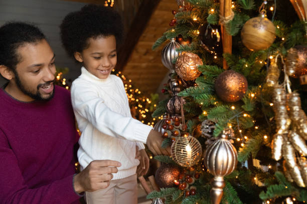 istock Happy biracial father and son decorate Christmas tree 1340098469
