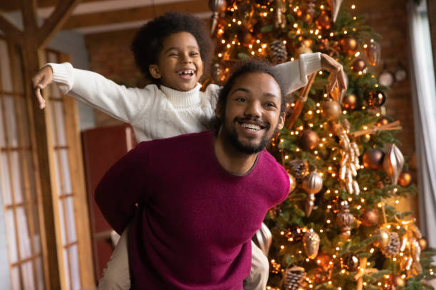 istock Overjoyed ethnic dad and son play near fir tree 1340098593
