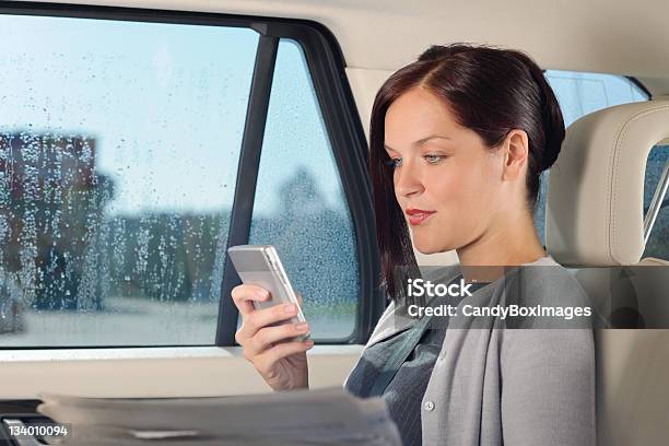 A Business Woman In A Car Using Her Mobile Phone Stock Photo - Download Image Now - Car Interior, Newspaper, Reading
