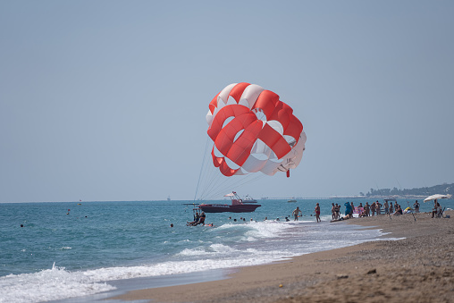 Side, Turkey - August  18, 2021: Parachute walk on the sea couple of loving people together on a yellow parachute over the water.