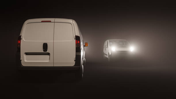 Rear View of a Mini Van with the Front View of Another in the Dark stock photo