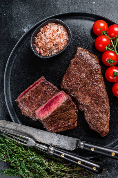 istock Roasted cut denver beef meat steak on a plate with thyme. Black background. Top view 1340106677