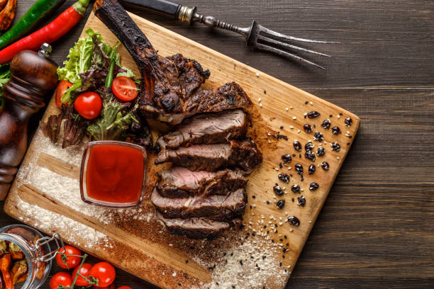 Grilled beef steak, herbs and spices on a dark table. Top view. Free space for your text. stock photo