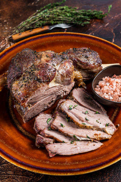 istock BBQ Roast Lamb mutton leg sliced on a rustic plate. Dark background. Top view 1340109705