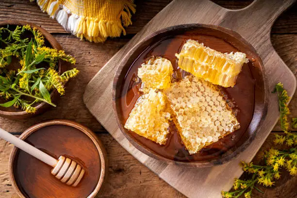 Delicious raw unpasteurized natural honecomb on a rustic wood table top.