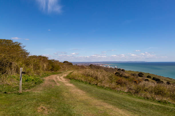 A Footpath in the South Downs along the Sussex Coast, with a Blue Sky Overhead Looking along a footpath on the Sussex coast, with Eastbourne in the distance east sussex stock pictures, royalty-free photos & images