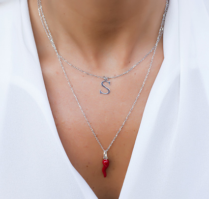 Double strand necklace worn. Red horn and initial letter of the name. Women's jewel